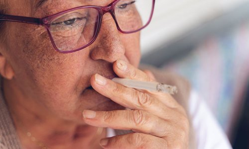 Äldre kvinnas deprimerad ut på ögonen och röker