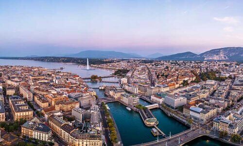 Flygfoto på staden Geneve där man ser en massa byggnader samt en hamn med vatten.