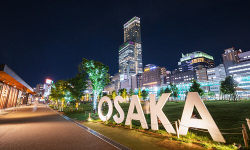 Bild på hus och stora bokstäver där det står Osaka. Bilden visar staden Osaka i Japan.