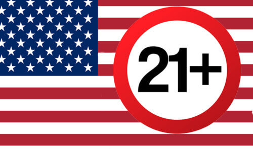 I bakgrunden en USA-flagga och på flaggan ligger en rund cirkel med siffrorna 21 och ett plus. Bilden gestaltar en åldersgräns på 21 år i USA på tobaksvaror.