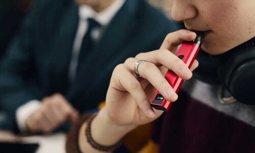 bild på person som använder en röd e-cigarett, bilden gestaltar att beroende hör ihop med vejpens styrka