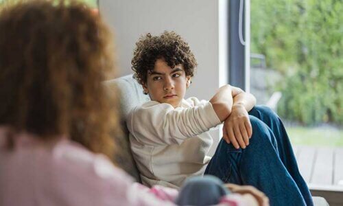 Bilde av en voksen og et barn som sitter i en sofa og snakker. Bildet viser motiverende samtaler med barn om nikotin.